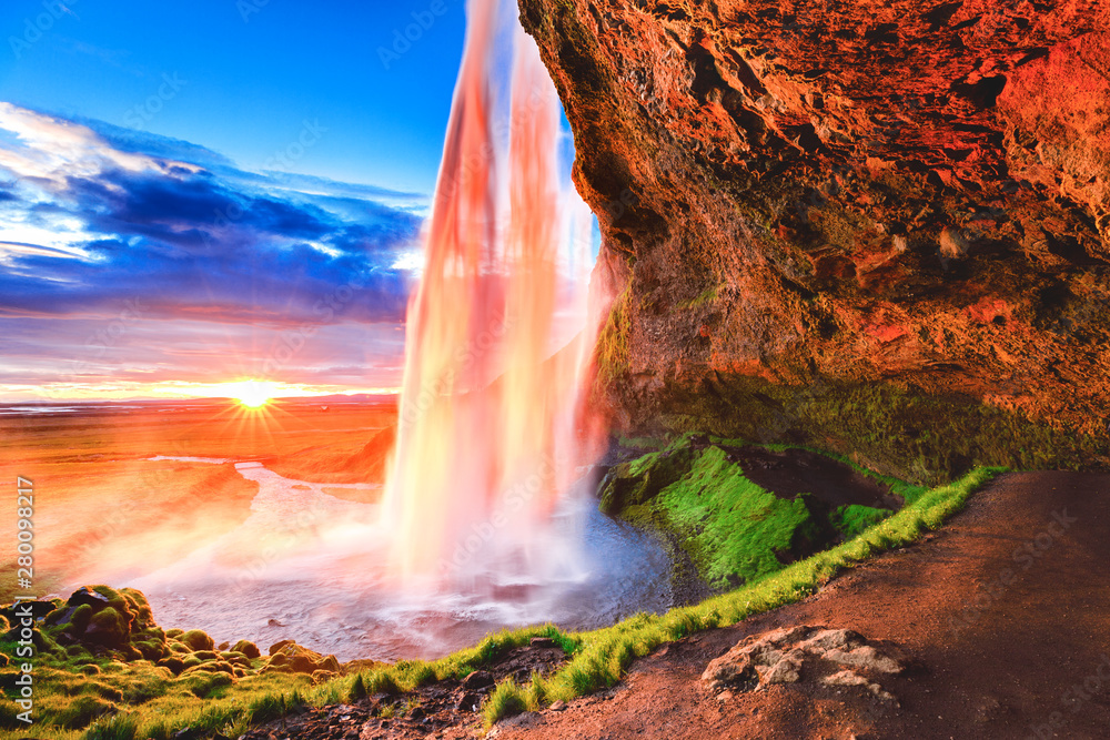 Seljalandsfoss waterfall in Iceland, Europe. Picturesque landscape photography in golden hour, day to night time, sun flare opposite of incredible Icelandic waterfall Seljalandsfoss - iconic landmark.