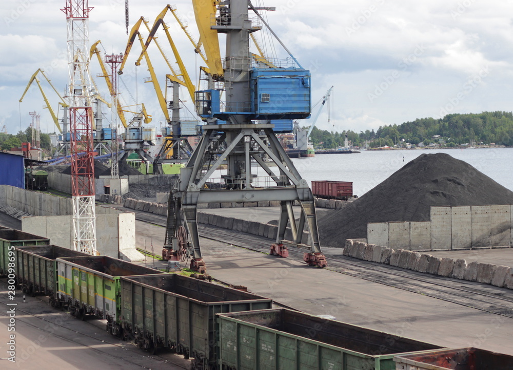 Port equipment concept. Industrial port with the railway and working cranes in the summer.