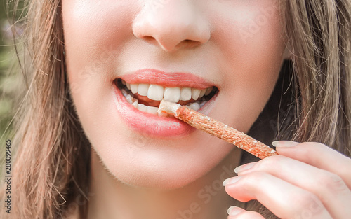Beautiful girl cleans her  healthy white teeth with eco miswak stick. Smiling woman uses  organic toothbrush at nature. Traditional  islamic arabian  teeth care with siwak.