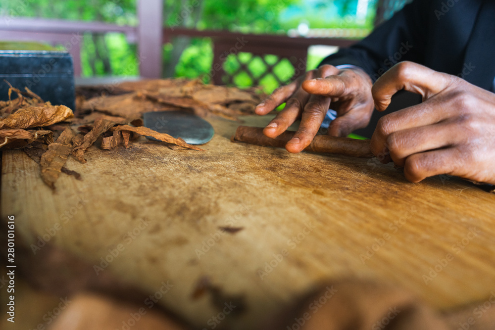 Process of making traditional cigars from tobacco leaves with hands using a mechanical device and press. Process of making traditional cigars from tobacco leaves with hands using a mechanical device and press.