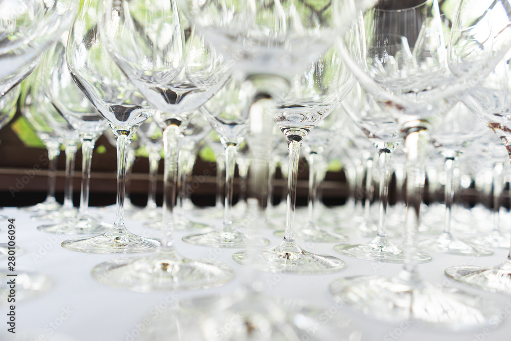 Several rows clear transparent, clean glasses for wine and champagne on counter prepared for drinks.