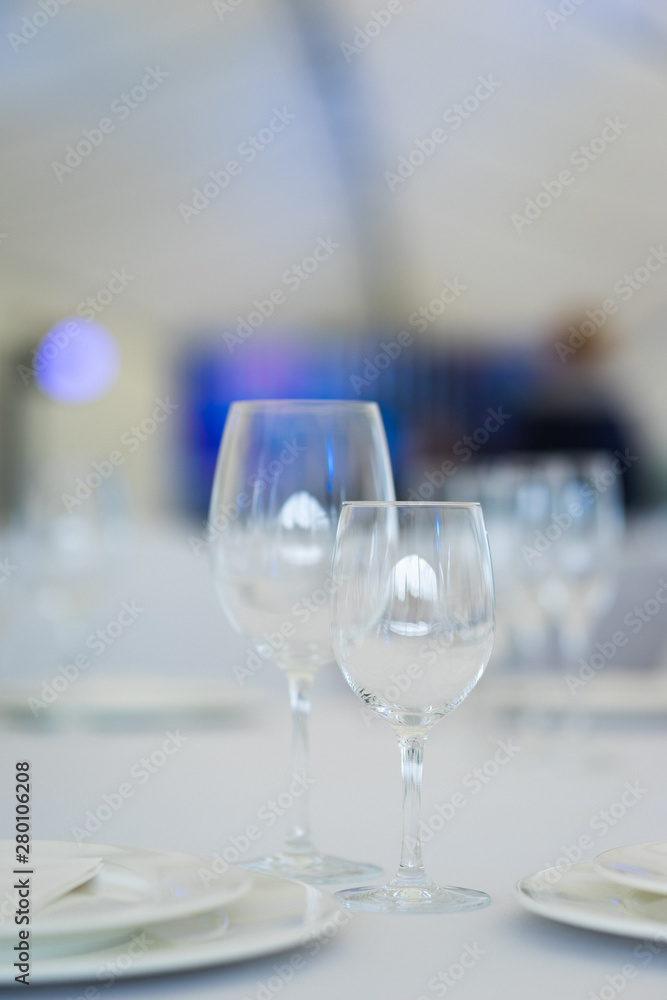 Obraz premium Clean empty glasses and plates on the table in the restaurant prepared for guests. 