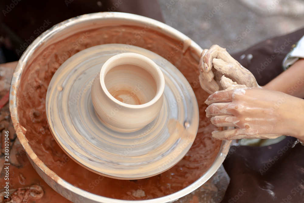 Close up pottery. Adult potter muddy hands guiding child hands to help with clay on a wheel Close up pottery. Adult potter muddy hands guiding child hands to help with clay on a wheel