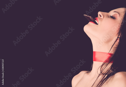 Tableau sur toile Beautiful woman eating dark chocolate with close eyes
