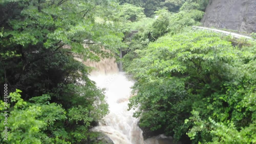 Rising over trees surrounding fast flowing mountain stream and waterfall