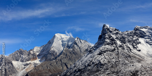 Chenadorje, holy snow mountain in Daocheng Yading Nature Reserve - Garze, Kham Tibetan Pilgrimage region of Sichuan Province China. Epic snow capped mountains, Blue Sky Background