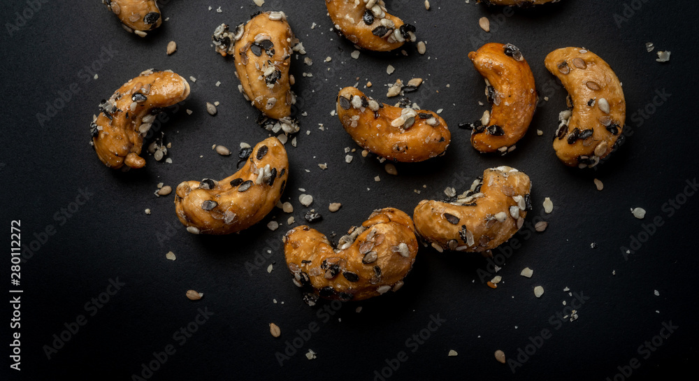 Naklejka premium Sesame Coated Cashew Nuts. Isolated on black background