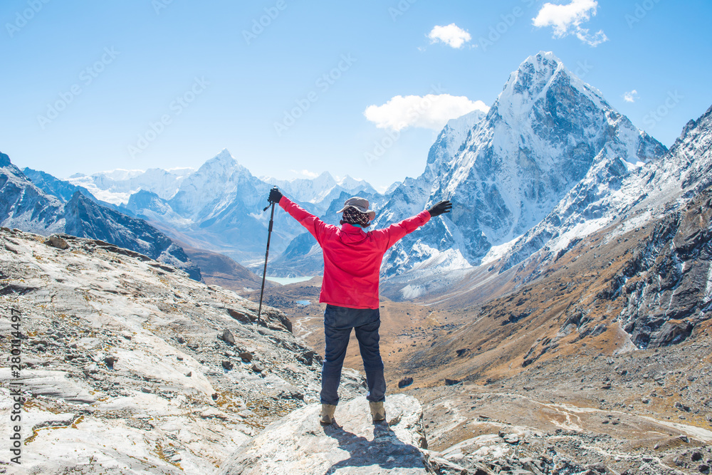 Back view of wanderlust woman standing at the edge of the mountain cliff and looking to the beautiful view of Mt.Ama Dablam (6,812 m) and Cholatse (6,440 m) view on the way to Cho La Pass, Nepal.  - obrazy, fototapety, plakaty 