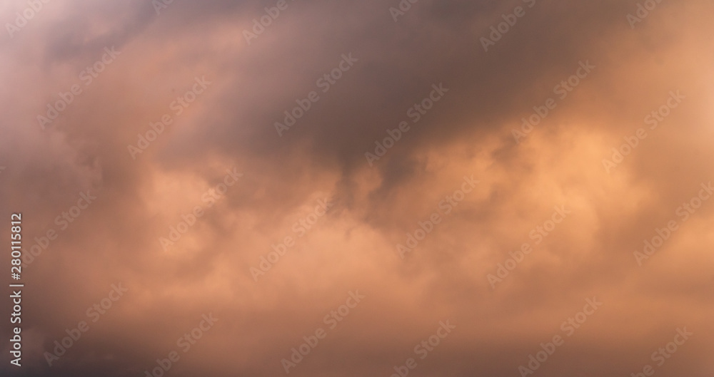 Panorama of stormy sky at twilight with clouds in various shades of orange and gray