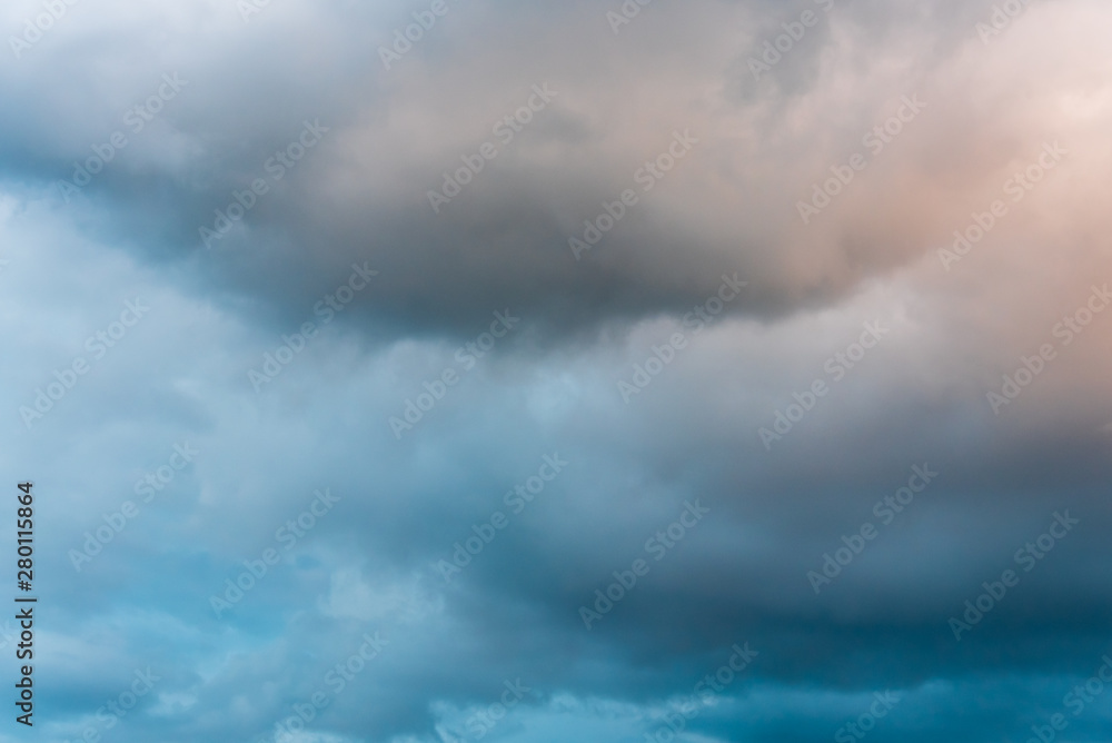 Obraz premium Stormy sky at twilight with clouds in various shades of blue, gray, and orange