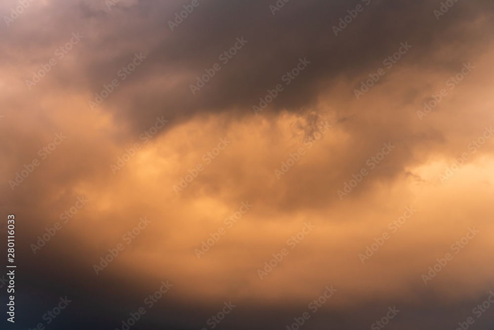 Stormy sky at twilight with clouds in various shades of orange and gray