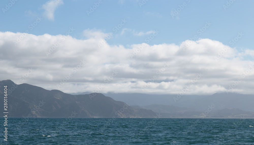 Delightful sea landscape with blue surface of the water, magic feather clouds on the sky over mountain in Kaikoura,New Zealand