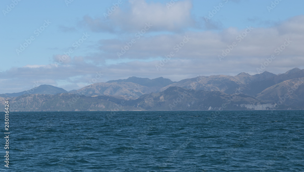 Delightful sea landscape with blue surface of the water, magic feather clouds on the sky over mountain in Kaikoura,New Zealand