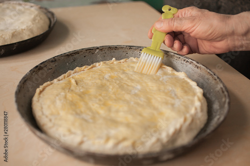 Woman lubricates an pie by egg. Top view