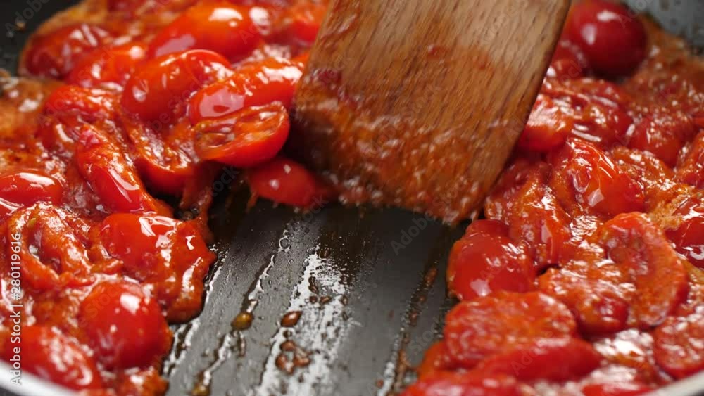 Thick tomato sauce bubbling in hot pan, wooden spatula splitting sauce