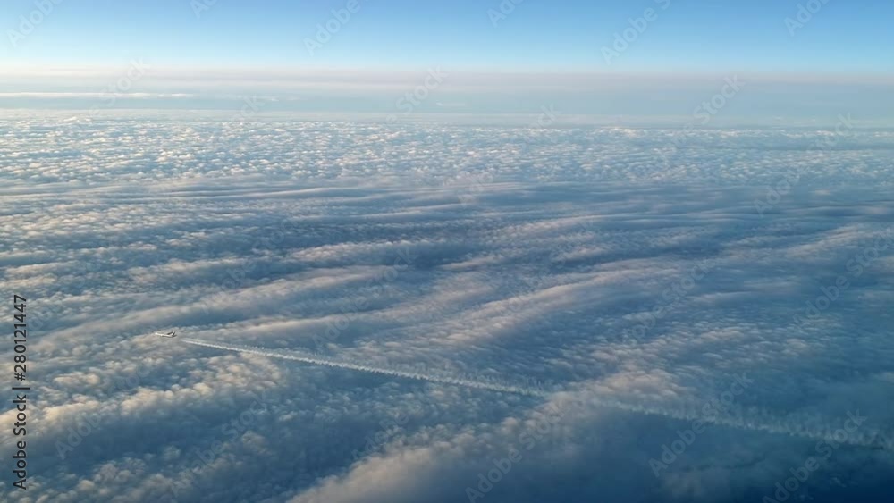 Incredible view from the cockpit of an airplane flying high above the clouds leaving a long white condensation vapour air trail in the blue sky. Zoom out 4k footage Incredible view from the cockpit of an airplane flying high above the clouds leaving a long white condensation vapour air trail in the blue sky. Zoom out 4k footage