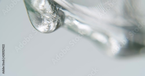 White transparent fluid forming slowly a drop. Fluids drips out of frame. Static macro shot. photo