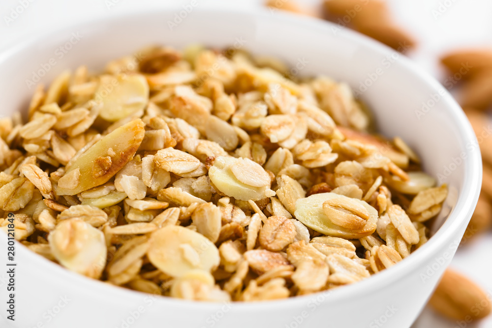 Homemade baked crunchy oatmeal, sliced almond, honey and coconut oil breakfast granola in bowl (Selective Focus, Focus in the middle of the granola) Homemade baked crunchy oatmeal, sliced almond, honey and coconut oil breakfast granola in bowl (Selective Focus, Focus in the middle of the granola)