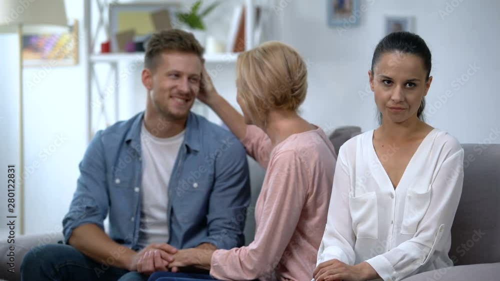 Pleasant young man talking with mother at home, while having quarrel with wife Pleasant young man talking with mother at home, while having quarrel with wife