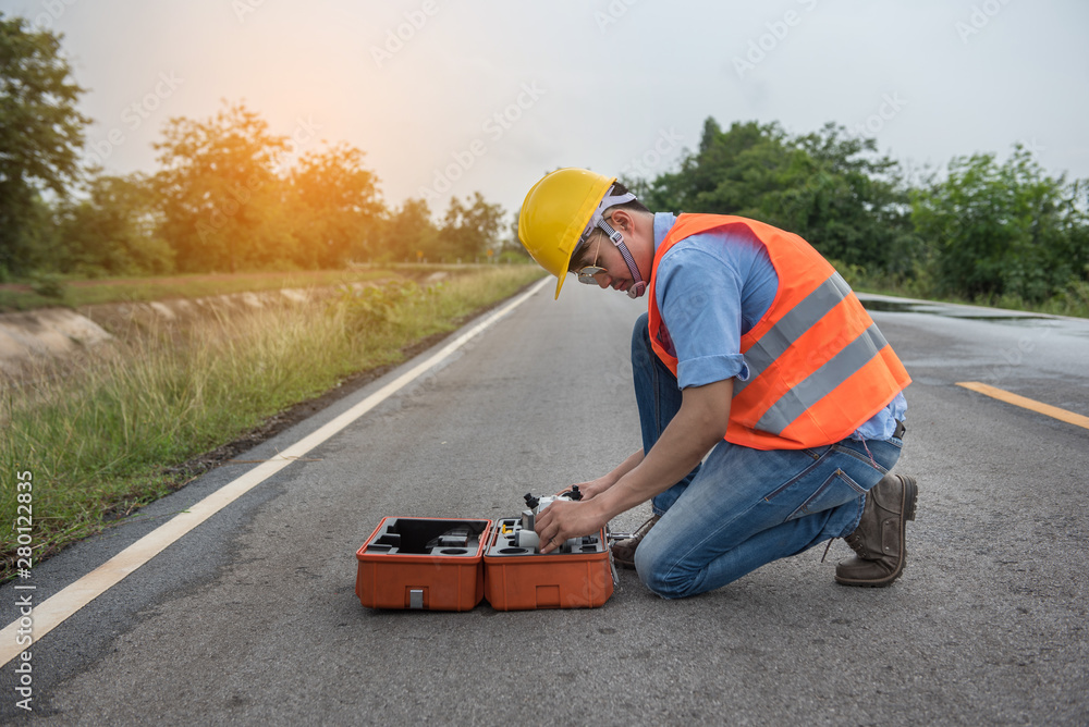 Civil engineer with Surveyor equipment tacheometer or theodolite outdoors at construction site on the road.
