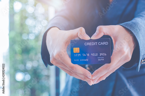 Female businessmen are holding a credit card and making a heart-shaped hand.