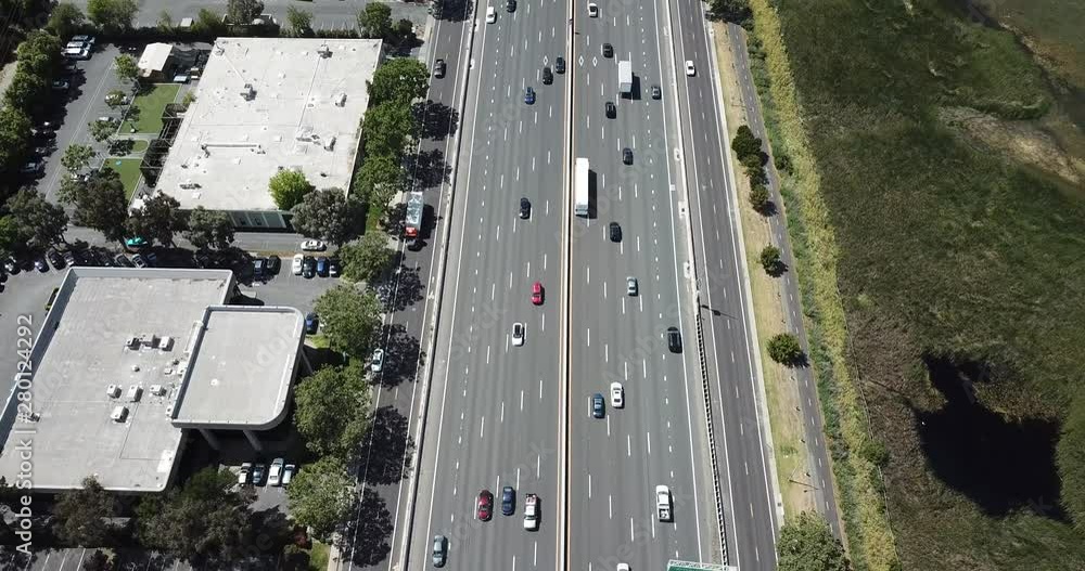 Aerial view of suburbs dense trees rooftop houses pine trees cars freeway 101 marsh on left tilt up Aerial view of suburbs dense trees rooftop houses pine trees cars freeway 101 marsh on left tilt up