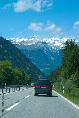 road with cars to snowy mountains horizon