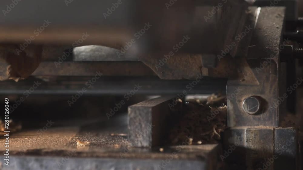 Carpenter putting small piece of wood into a big carpentry machine. Carpenter putting small piece of wood into a big carpentry machine.