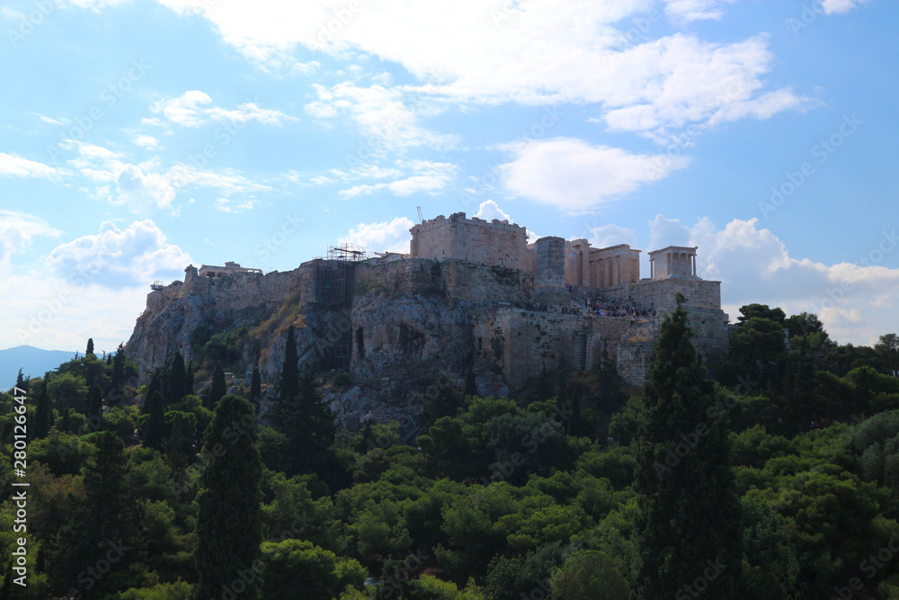 Fantastic panoramic aerial view to ancient greek landmark acropolis of athens situated on the hill and surrounded by green trees under blue sky with clouds