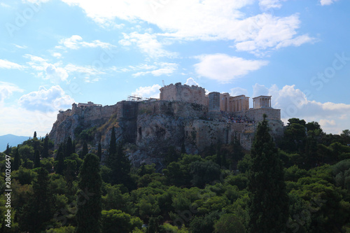 Fantastic panoramic aerial view to ancient greek landmark acropolis of athens situated on the hill and surrounded by green trees under blue sky with clouds