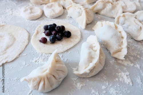 Sculpted dumplings with Irga, raw dough. Stages of preparation of sweet flour boiled dishes. White table with flour and roll the dough.