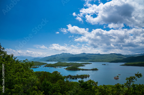 Montenegro, Mountains covered by green trees and forest surrounding seascape of lake slano peninsulas near niksic city from above