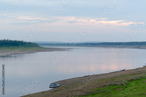 Boats standing on the stone shore turn wild North of the river Vilyui misty night in a deserted taiga of Yakutia.