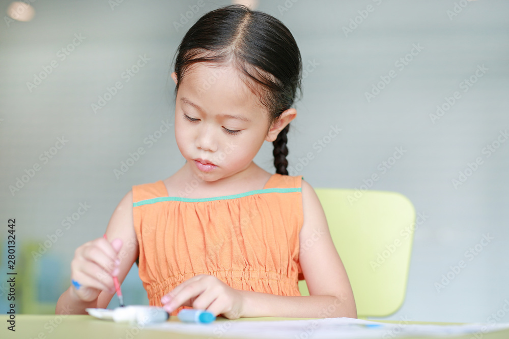 Adorable little Asian girl drawing and painting with water color on paper in children room Adorable little Asian girl drawing and painting with water color on paper in children room