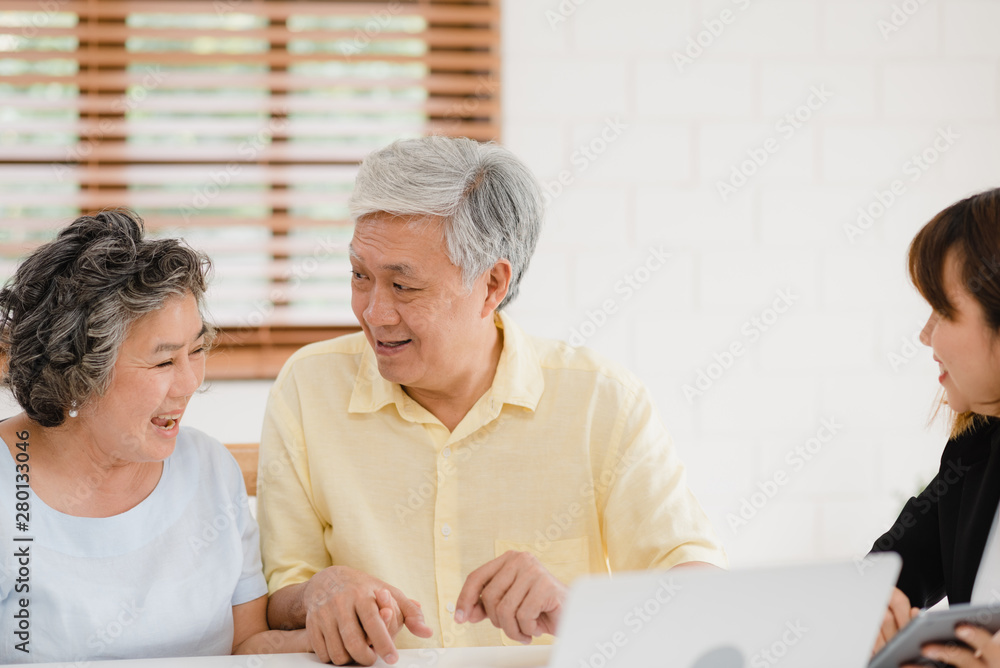 Obraz premium Asia smart female agent offers health insurance for elderly couples by document, tablet and laptop. Aged Asian couple consulting with insurance agent while sitting together with at home.