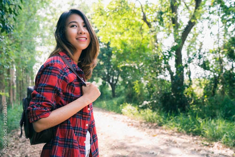 Happy young Asian woman traveler with backpack walking in forest. Hiker Asian woman with backpack walking on path in summer forest. Adventure backpacker travel people concept. Happy young Asian woman traveler with backpack walking in forest. Hiker Asian woman with backpack walking on path in summer forest. Adventure backpacker travel people concept.