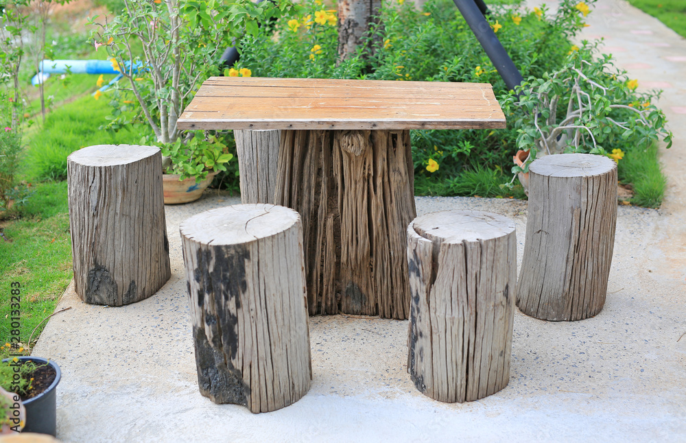Fototapeta premium Wood table and chair set in garden. Garden furniture made from wooden log.