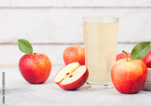 Glass of fresh organic apple juice with braeburn pink lady apples in box on wooden background