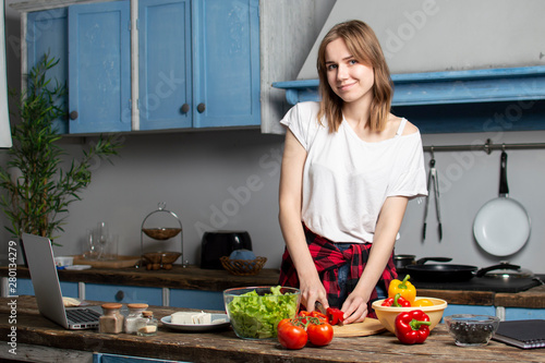 young girl prepares a vegetarian salad in the kitchen, the process of preparing healthy food