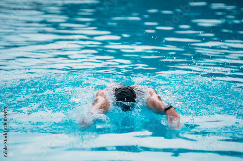 Professional man swimming in butterfly style with hat and goggles at the pool © ManuPadilla