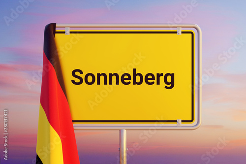 Sonneberg. Gelbes Schild/Ortsschild. Flagge von Deutschland hängt darüber. Himmel mit Sonnenuntergang oder Sonnenaufgang photo