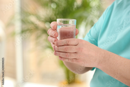 Closeup view of elderly man with glass of water in nursing home, space for text. Assisting senior generation