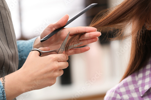 Barber making stylish haircut with professional scissors in beauty salon  closeup