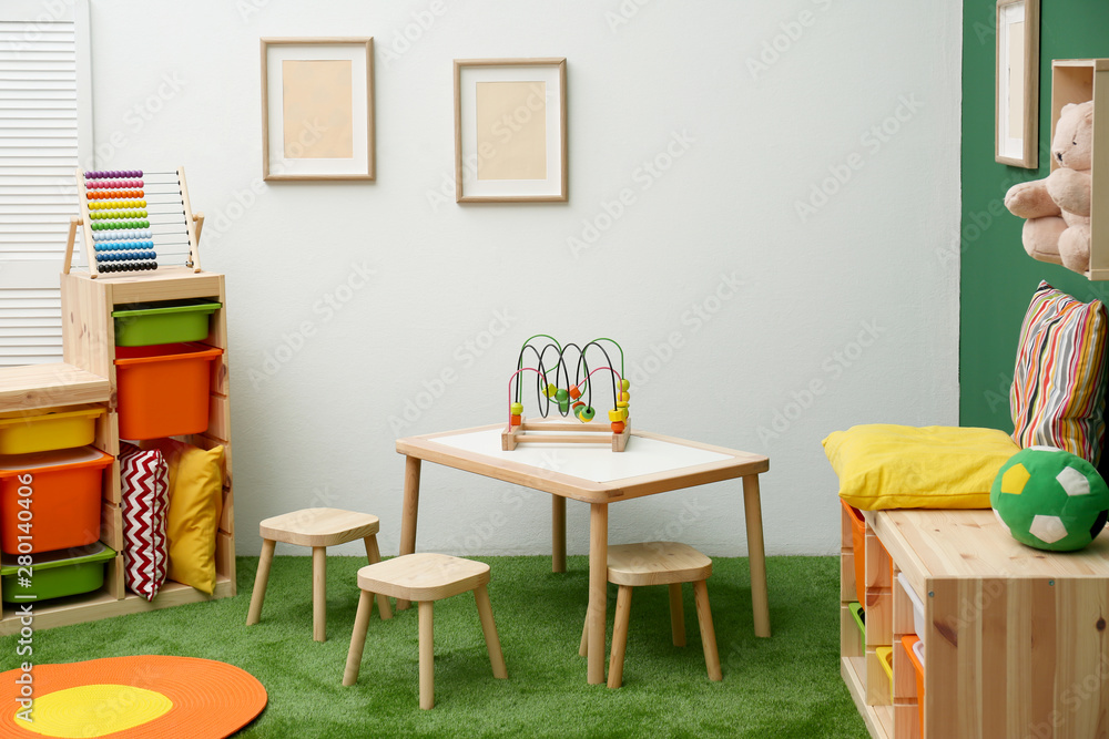 Fototapeta premium Stylish playroom interior with table and stools