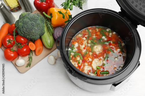 Modern multi cooker and products on white wooden table, above view
