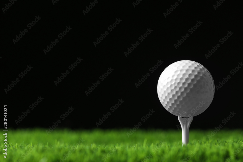 Golf ball with tee on artificial grass against black background, space for text Golf ball with tee on artificial grass against black background, space for text