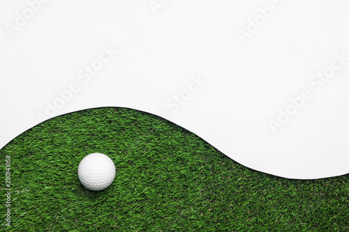 Golf ball and white paper on green artificial grass, top view with space for text