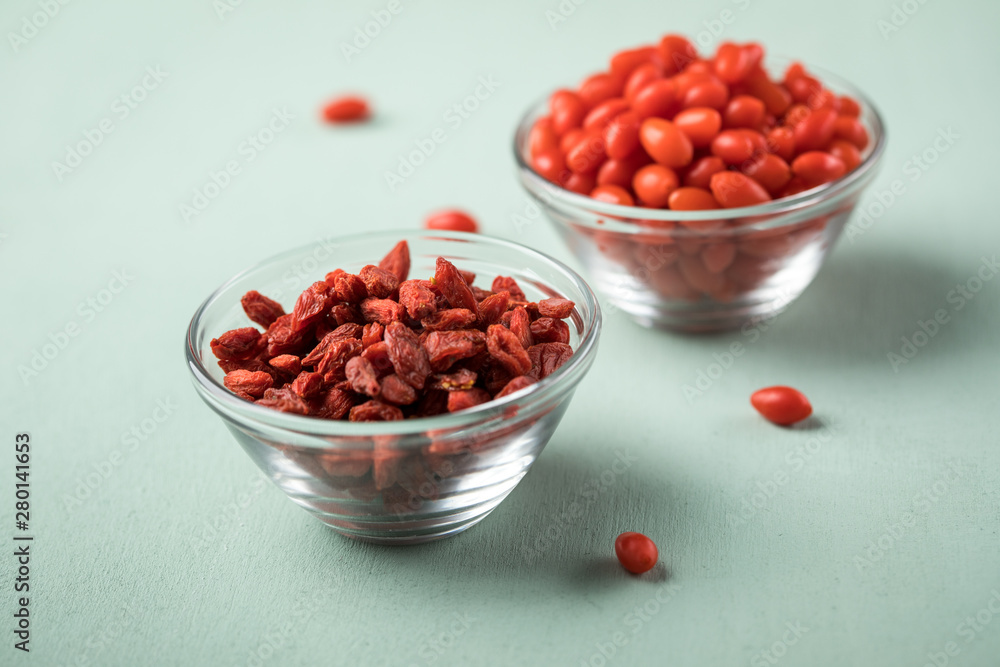 Frische und getrocknete Goji-Beeren Superfood in Glas Schale auf Mint Grün Pastell Hintergrund Frische und getrocknete Goji-Beeren Superfood in Glas Schale auf Mint Grün Pastell Hintergrund