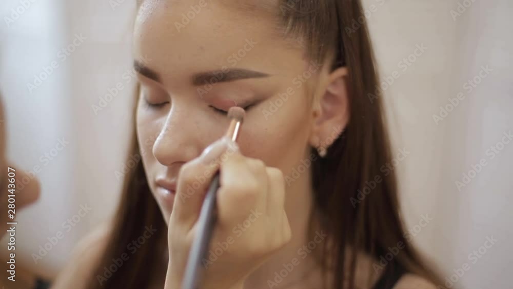 Makeup artist applies eye shadow, perfect evening makeup. Beauty redhead girl with perfect skin and freckles Makeup artist applies eye shadow, perfect evening makeup. Beauty redhead girl with perfect skin and freckles