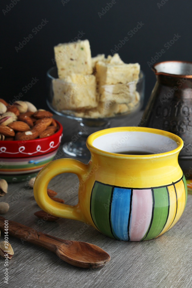 A mug of coffee and different oriental sweets: turkish delight, halva, almond and pistachio A mug of coffee and different oriental sweets: turkish delight, halva, almond and pistachio